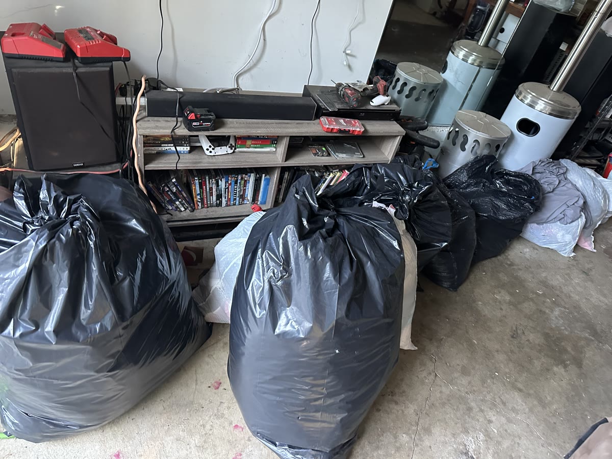 Bagged clothing donations stacked across the garage floor, waiting to be sorted.